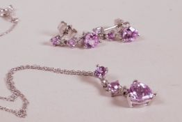 A 10ct white gold necklace with pink sapphire heart shaped pendant and matching drop earrings