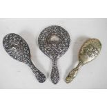 A silver backed late C19th mirror and brush dressing table set, with repousse scrolls, birds and