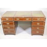 A campaign style mahogany nine drawer pedestal desk with three panel leather writing surface over