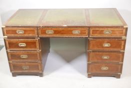 A campaign style mahogany nine drawer pedestal desk with three panel leather writing surface over