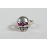 A 925 silver skull ring with ruby set eyes, approximate size 'O'