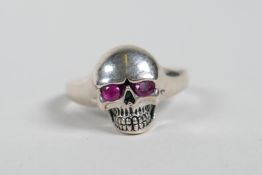 A 925 silver skull ring with ruby set eyes, approximate size 'O'