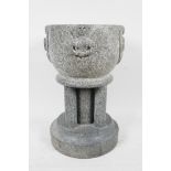 A green stone pedestal font in Romanesque style, with hand carved angel decoration around the