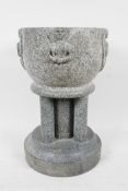 A green stone pedestal font in Romanesque style, with hand carved angel decoration around the