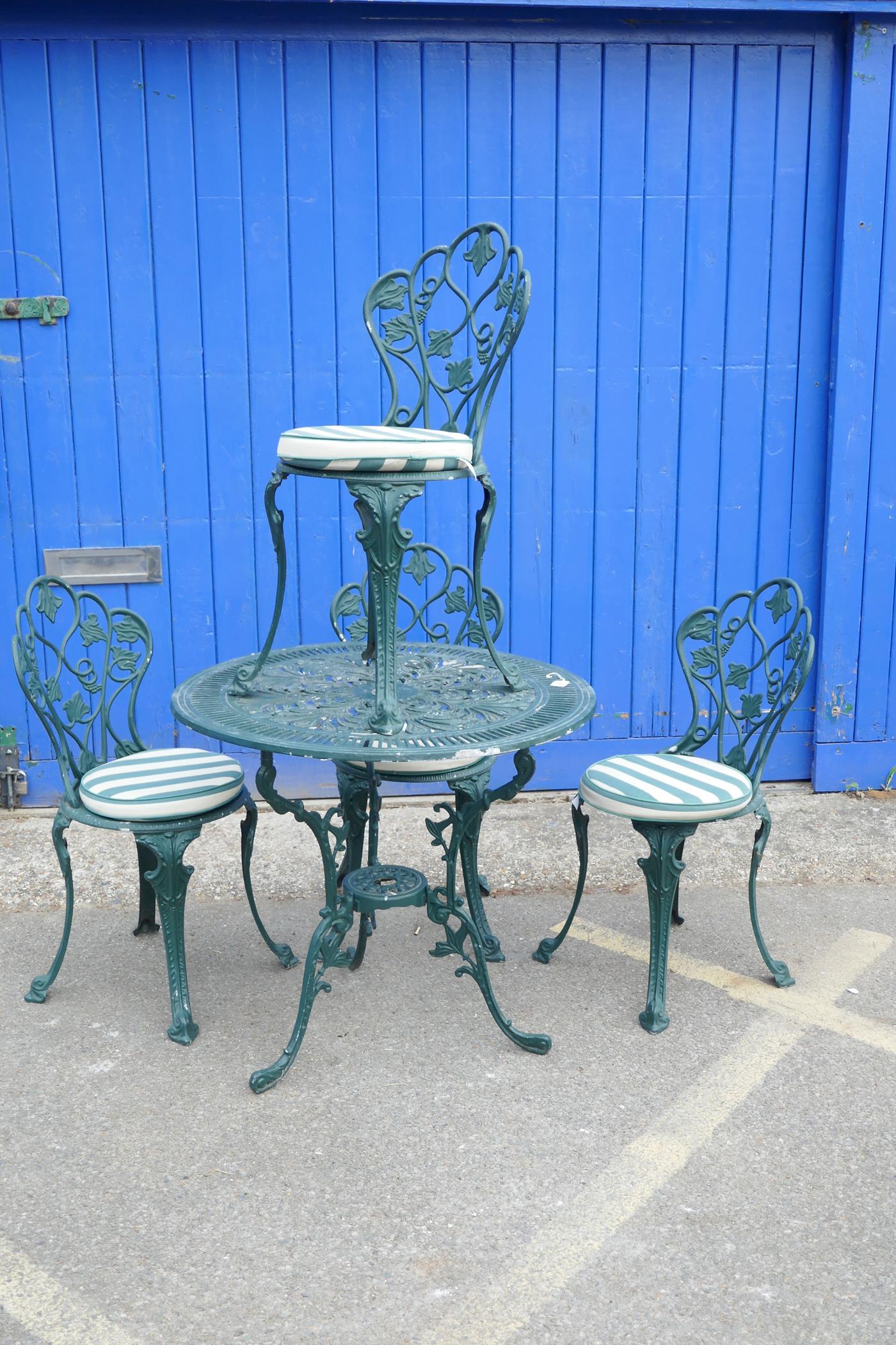 A cast aluminium garden table and chairs, the circular table with pierced decoration and three leg