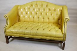 A Chippendale style buttoned leatherette two seater settee with brass studs and carved back and