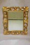 A carved giltwood Florentine style wall mirror with bevelled glass, mid C20th, 25" x 30"