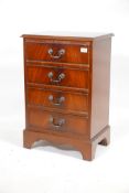 A mahogany veneered chest of four long drawers, with brass handles, raised on bracket supports,