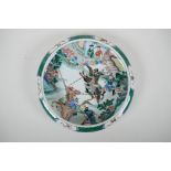 A Chinese famille verte porcelain dish with a rolled rim decorated with warriors on horseback, 6