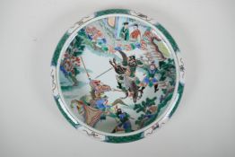 A Chinese famille verte porcelain dish with a rolled rim decorated with warriors on horseback, 6