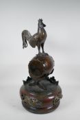 A Japanese Meiji (1868-1912) bronze of a cockerel standing on a war drum, the base with pierced