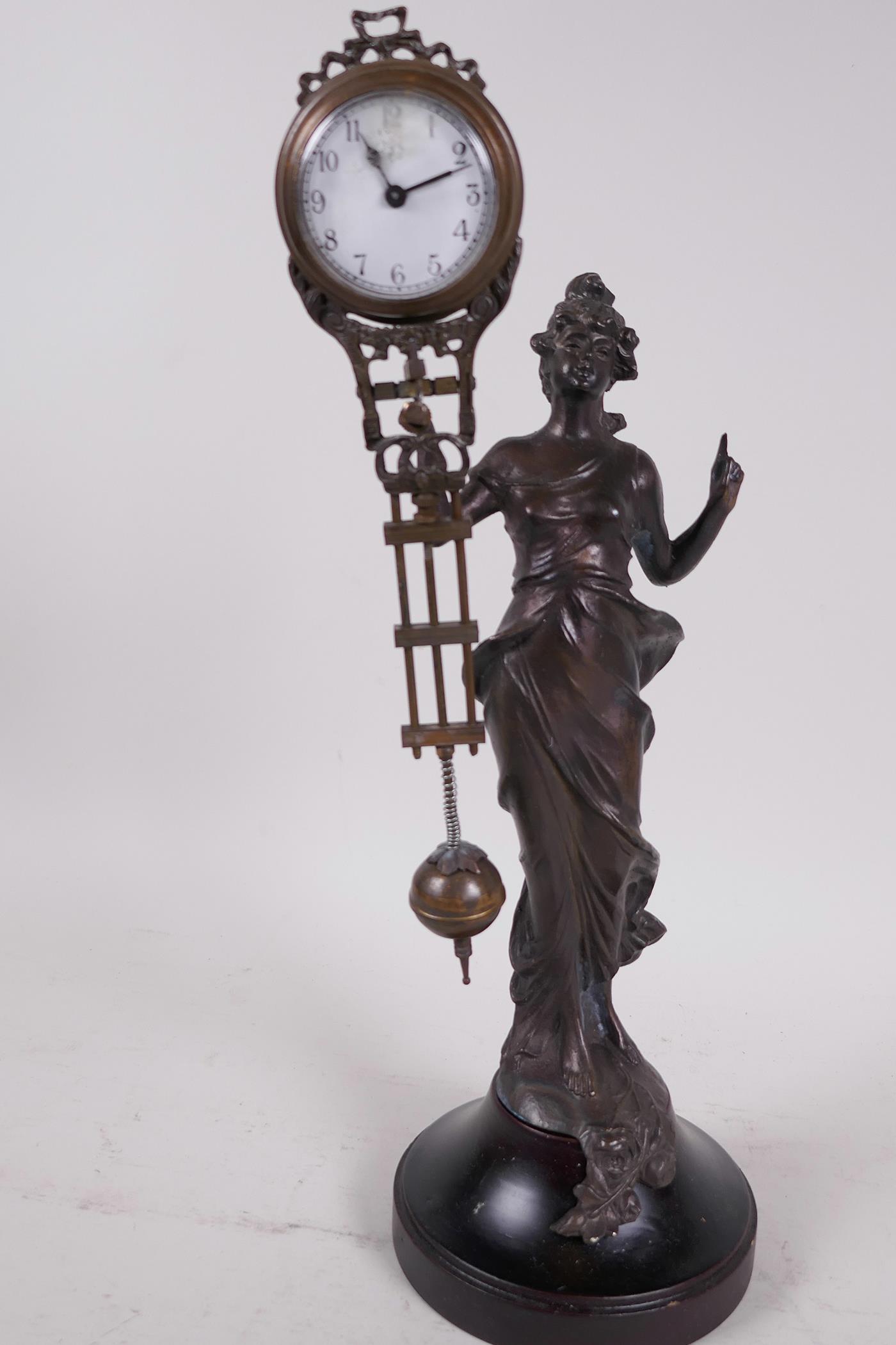 A bronze mystery clock cast as an Art Nouveau style lady with the clock raised on one arm, 13" high