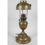 A brass table lamp made in the form of a classical urn shaped oil lamp with brass shade set with