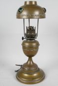 A brass table lamp made in the form of a classical urn shaped oil lamp with brass shade set with