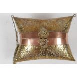 An Indian brass cushion shaped shoulder purse with engraved floral decoration, coppered bands and