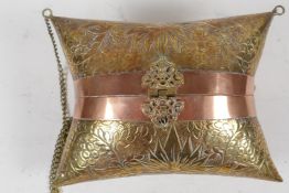 An Indian brass cushion shaped shoulder purse with engraved floral decoration, coppered bands and