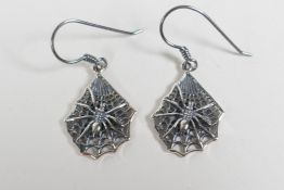 A pair of silver drop earrings with spider decoration