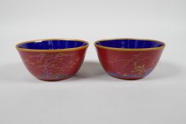 A pair of Chinese red ground porcelain tea bowls with polychrome decoration of flowers, foliage