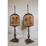 A pair of C19th mahogany pole screens with carved frames containing floral embroideries, on a turned