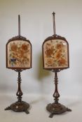 A pair of C19th mahogany pole screens with carved frames containing floral embroideries, on a turned
