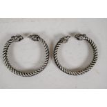 A pair of Chinese twisted white metal bangles with cast dragon's head ends, 2" diameter