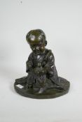 A patinated bronze figure of an Oriental child holding a doll, 12" high