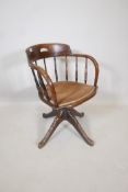 An Edwardian swivel desk chair in oak with upholstered seat and pedestal base with four feet, A/F,