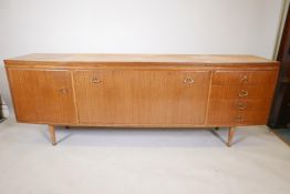 A mid century bowfront teak sideboard with a fall front centre section flanked by a flight of four
