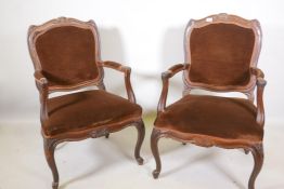 A pair of Continental walnut open armchairs on scroll feet with carved details, 38" high