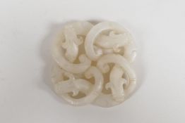 A Chinese white jade pendant carved in the form of entwined dragons, 2" x 2"