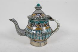 A Moorish ceramic and white metal teapot encased with wire metal and painted with a traditional