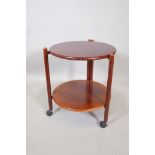 A mid century mahogany two tier occasional table, with folding base, raised on turned supports