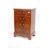 A mahogany veneered chest of four long drawers, with brass handles, raised on bracket supports,