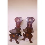 A pair of Georgian inlaid mahogany hall chairs, with shaped backs, and painted crests and