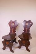 A pair of Georgian inlaid mahogany hall chairs, with shaped backs, and painted crests and