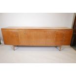 A mid century bowfront teak sideboard with a fall front centre section flanked by a flight of four