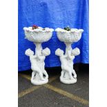 A pair of painted concrete raised garden planters, the planters held aloft by two cherubs, 36" high,