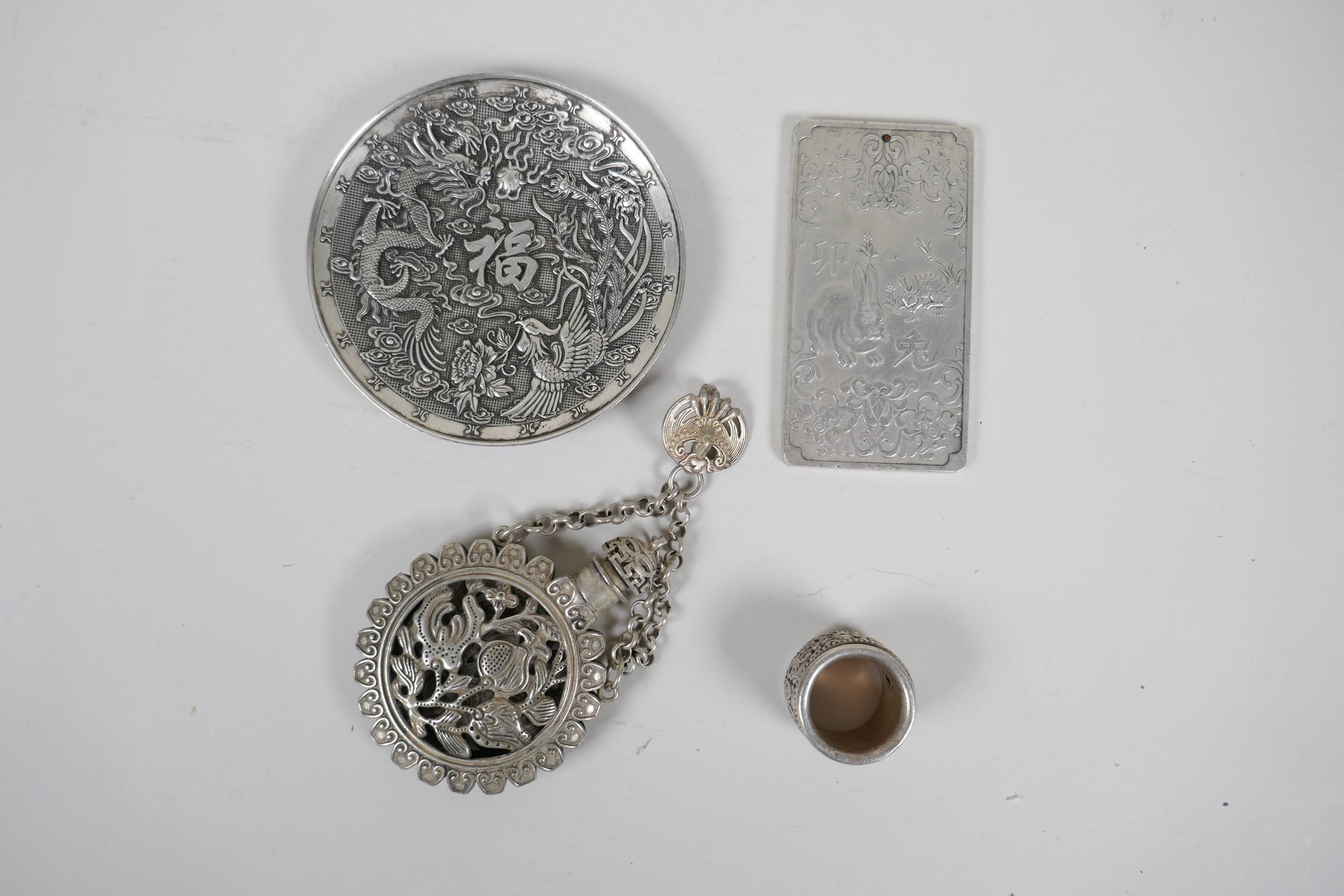 A collection of four Chinese white metal items to include a trinket dish with dragon decoration,