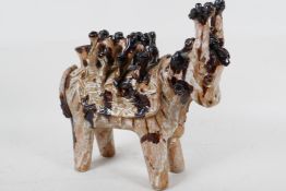An unusual studio pottery figure of an Indian cow with elaborate saddle, part treacle glazed, 10"
