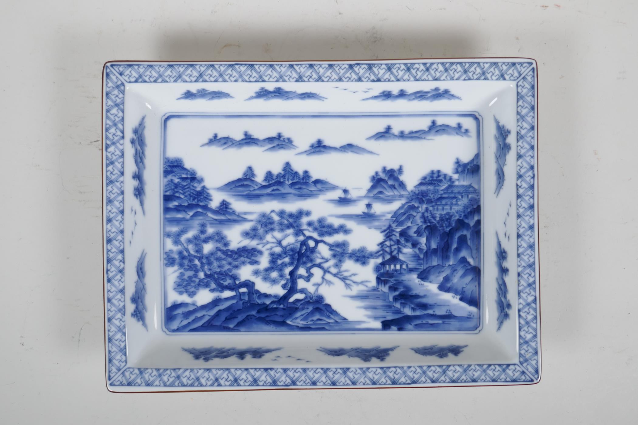 A Chinese blue and white porcelain shallow dish of rectangular form, decorated with a riverside