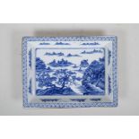 A Chinese blue and white porcelain shallow dish of rectangular form, decorated with a riverside