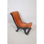 A Victorian ebonised slipper chair, with rust red upholstery and brass decorative motifs and trim,