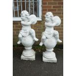 A pair of painted garden statues in the form of putti atop balls, 40" high