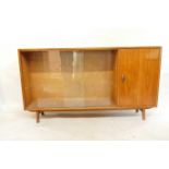 A mid C20th teak side cabinet with single door and two sliding glass doors, bears label Herbert E.