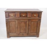 An antique oak side cabinet, with panelled ends and cupboards under three drawers, C18th and later
