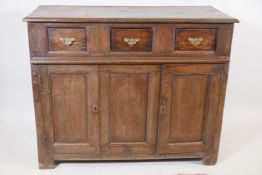 An antique oak side cabinet, with panelled ends and cupboards under three drawers, C18th and later