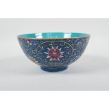 A Chinese polychrome porcelain rice bowl with enamelled scrolling lotus flower decoration on a
