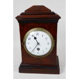 A C19th walnut cased mantel clock of architectural form with timepiece movement, white enamel dial