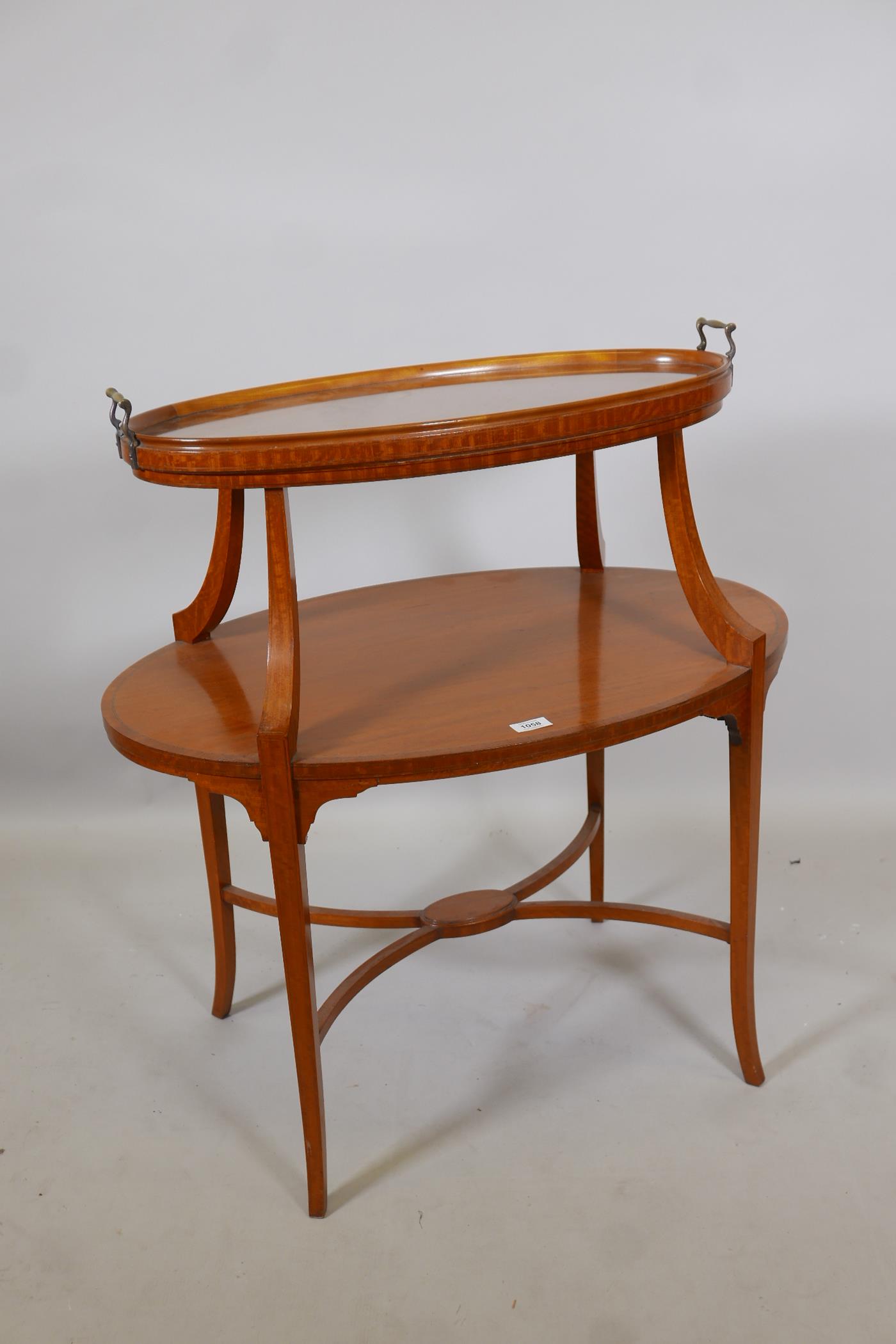 A C19th satinwood two tier etagere, the top with removable glass tray, raised on sabre supports