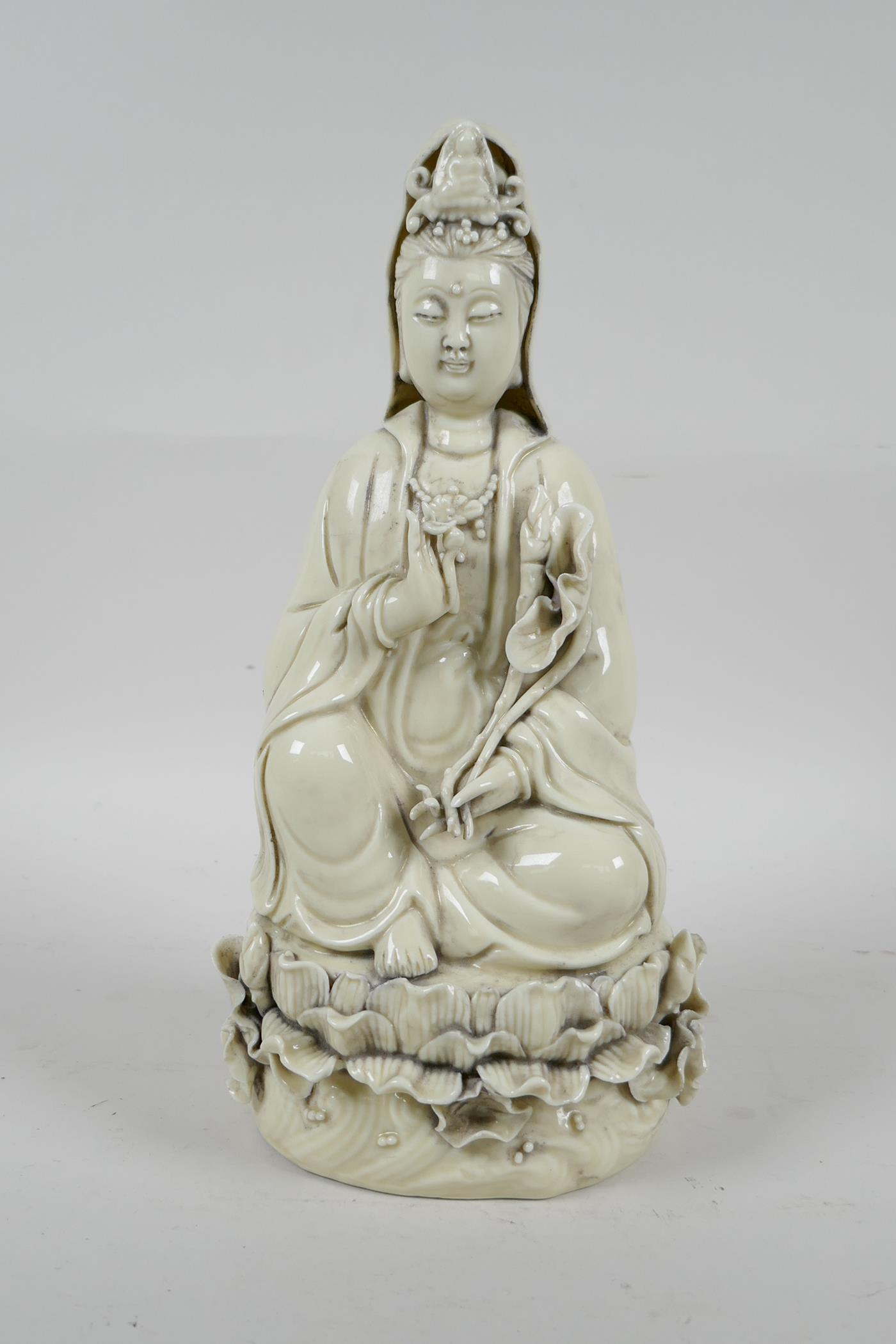 A Chinese blanc de chine porcelain Quan Yin seated on a lotus throne, impressed marks verso, 10½"